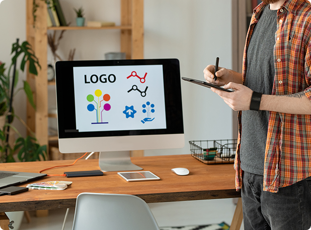 Graphic designer elaborating a logo, a desktop, and a wooden table