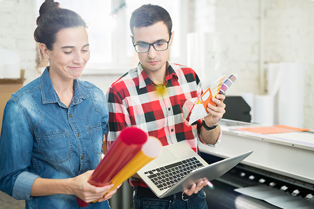 Two designers are choosing color palettes and holding a laptop 